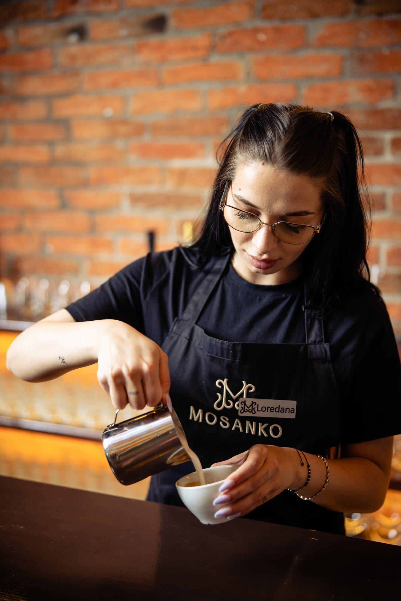 Barista Mosanko toarnă laptele în ceașcă